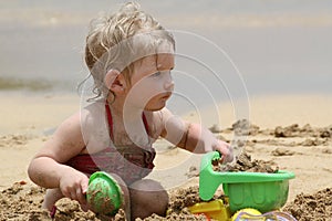 Bambina giocando in spiaggia con la sua sabbia giocattoli.
