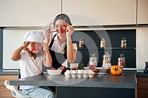 Playing with slices of pepper. Mother with her daughter are preparing food on the kitchen