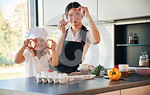 Playing with slices of pepper. Mother with her daughter are preparing food on the kitchen