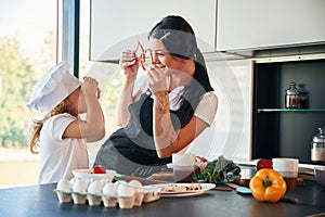 Playing with slices of pepper. Mother with her daughter are preparing food on the kitchen