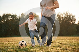 Playing soccer. Father and little son are having fun outdoors