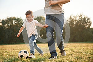 Playing soccer. Father and little son are having fun outdoors