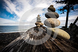 Playing with stacking rocks on a log at Agate Beach, Haida Gwaii, British Columbia, Canada