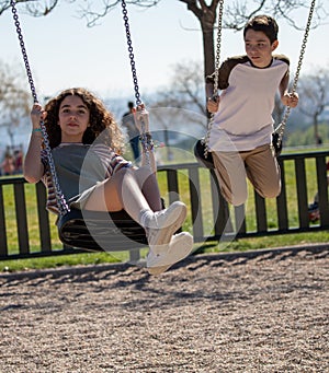 Playing on a swing in a park with her brother