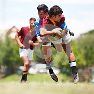 Playing to win. Full length shot of a young rugby player trying to avoid a tackle.