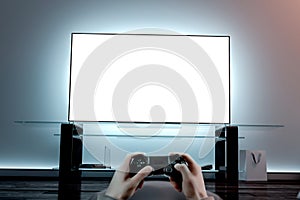 Playing videogame with joystick near blank white tv screen mockup