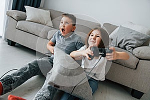 Playing videogames. Kids having fun in the domestic room at daytime together