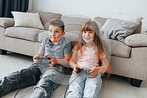 Playing videogames. Kids having fun in the domestic room at daytime together