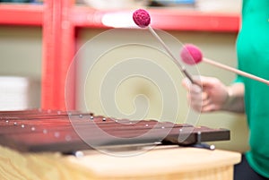 Playing a xylophone musical instrument. Shallow depth of field. Focus on the farthest musical stick