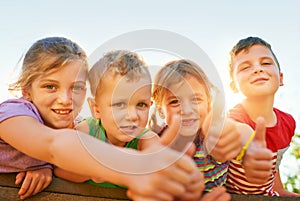Playtime is the best time. Portrait of a group of little children showing thumbs up while playing together outdoors.