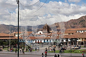 The Plaza de Armas center square with fountain with Peruvians and tourists going about their day in Cusco, Peru