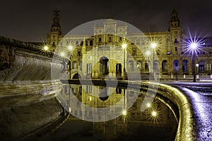 Plaza de EspaÃ±a in Seville, night scene after raining with long exposure photo and reflections of lights in water and cobbled