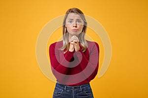 Pleading young blonde woman girl in casual clothes posing isolated on yellow orange background studio portrait. People