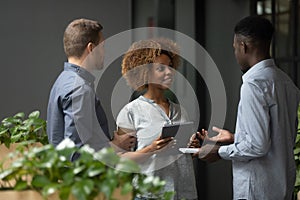 Pleasant african american female employee talking with mixed race colleagues.