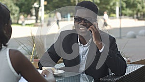 Pleasant afro american man having phone call during work break with his calleague