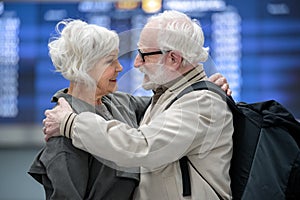 Pleasant aged couple is embracing in terminal