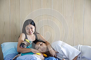 Pleasant asian couple sleeping while resting with their pug dog in bed