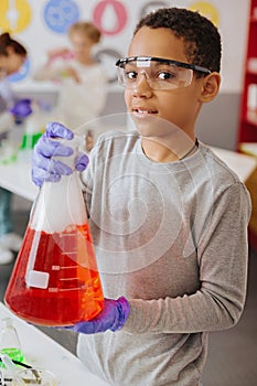 Pleasant boy posing with a big chemical flask in lab