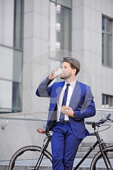 Pleasant businessman standing with bicycle
