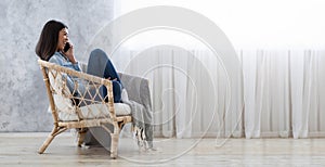 Pleasant Call. Cherful Asian Woman Talking On Cellphone While Resting In Armchair photo