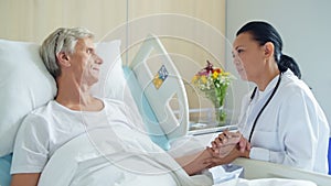 Pleasant caring doctor supporting his aged inpatient