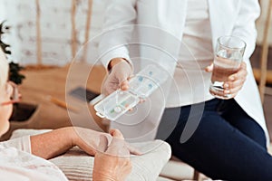 Pleasant caring nurse giving pills to an elderly woman