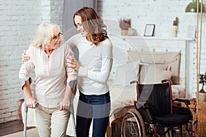 Pleasant caring woman helping with rehabilitation her disabled grandmother