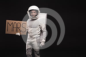 Pleasant cosmonaut is posing with cardboard