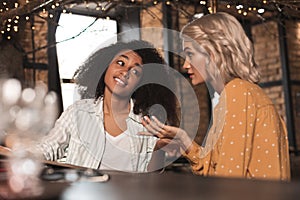 Pleasant curly woman listening to her friends story skeptically