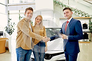 Pleasant customers shake hand to responsive consultant of cars dealership