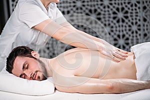 Pleasant dark-haired guy is getting massage for spine