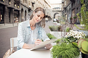 Pleasant delighted woman sitting at the table outside