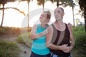 Pleasant, delightful mature woman and man basking in the warm sunlight stand together in tropical jungle, on journey