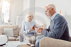 Pleasant elderly couple being glued to their phones