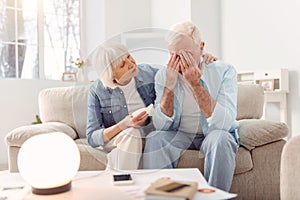 Pleasant elderly woman cheering up her crying husband