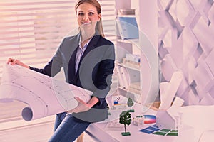 Pleasant female architect unrolling blueprint at office