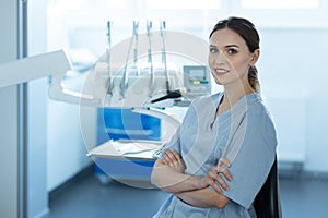 Pleasant female dentist posing in her office