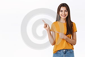 Pleasant, friendly-looking pretty caucasian woman in yellow t-shirt pointing upper left corner, help customer find way