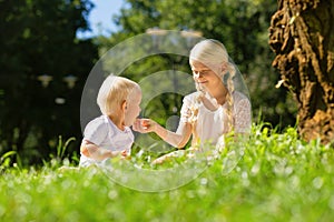 Pleasant girl feeding a small boy with a cake