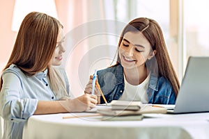 Pleasant girl helping her sister with home assignment