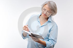 Pleasant grey-haired woman reading her notes