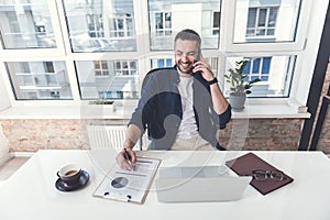 Pleasant joyful manager is enjoying conversation on mobile phone