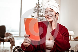 Pleasant joyful woman having enjoyable conversation through tablet