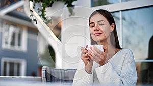 Pleasant lady drinking hot tea enjoying fragrance on terrace. Medium close up shot on 4k RED camera