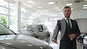 A pleasant-looking young salesman-consultant in a business suit presents new cars