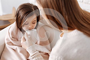 Pleasant loving mother helping little girl to recover