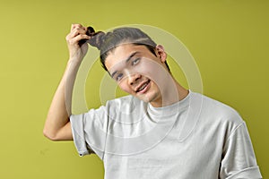 pleasant male model touching hair in topknot and looking at camera isolated on green