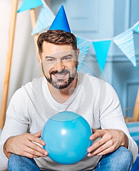 Pleasant man in party hat posing with balloon