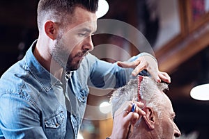 Pleasant nice barber combing his clients hair