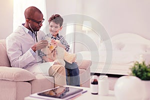 Pleasant nice doctor putting stethoscope to the toy